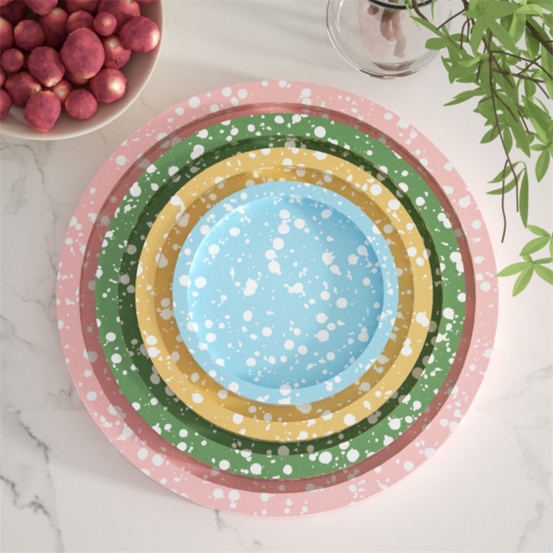 May include: Set of four nesting plates with a speckled design. The plates are pink, green, yellow, and blue with white speckles.