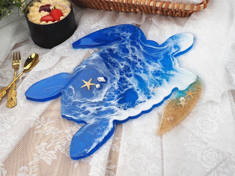 May include: A blue resin turtle tray with white and blue waves, a sandy beach section, and seashells.