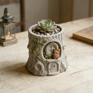 Könnte beinhalten: Ein grauer Baumstumpf-Pflanztopf mit einer Sukkulentenpflanze. Der Pflanztopf hat eine kleine Tür und ein Fenster mit einer Eichhörnchenfigur. Grüne Ranken und Blätter verzieren die Seite. Der Pflanztopf ist mit kleinen Steinen gefüllt.