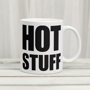 May include: White ceramic mug with a black inscription that reads "HOT STUFF".