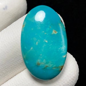 May include: A smooth, oval-shaped turquoise cabochon with a light blue color and brown matrix. The stone has a polished finish.