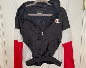 May include: Black, white, and red color block windbreaker jacket with a Champion logo on the left chest. The jacket has a zipper closure and a hood.