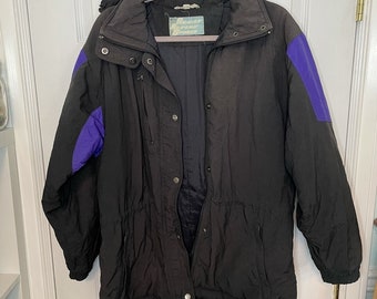 May include: Black winter jacket with purple shoulder accents. The jacket has a hood, multiple pockets, and a button and zipper closure. The label reads "Great Alpine Sports".