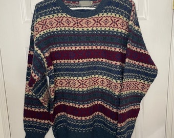 May include: A blue, red, white, and cream patterned sweater with a crew neck.