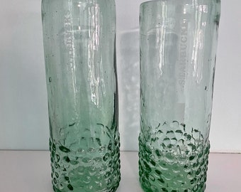 May include: Two clear glass drinking glasses with a textured, bubbled surface. The glasses are empty and have a green tint.