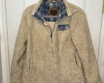 May include: A cream-colored sherpa jacket with a blue and white plaid lining. The jacket has a zipper closure and a patch pocket on the left chest. The label on the jacket reads "Pendleton".