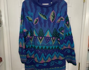 May include: A blue, green, and pink patterned sweater with a high neck. The sweater has a geometric design with leaves and swirls.