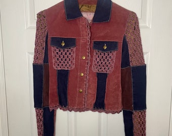 May include: A burgundy suede jacket with crocheted sleeves and a blue denim collar. The jacket has a button closure and two pockets.