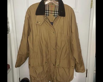 May include: A tan, long-sleeved jacket with a brown corduroy collar and a plaid lining. The jacket has a zipper closure, multiple pockets, and a button-up front.