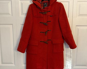 May include: A red wool duffle coat with a hood and toggle closures. The coat has a plaid lining and two large pockets.