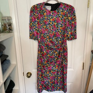 May include: A black floral print dress with a gathered waist and short sleeves. The dress has a label that reads "Fink's Montreal".