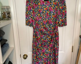 May include: A black floral print dress with a gathered waist and short sleeves. The dress has a label that reads "Fink's Montreal".
