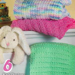Op de afbeelding: Een boek getiteld "Easy Timeless Blankies" door Kathy Sasser, met zes breipatronen voor baby's en peuters. De omslag toont een stapel kleurrijke gebreide dekens en een knuffelkonijn.