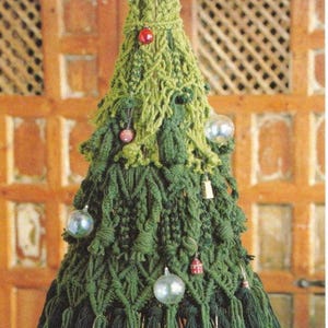 K&ouml;nnte beinhalten: Ein gr&uuml;ner Weihnachtsbaum aus Garn, der mit roten und wei&szlig;en Kugeln geschm&uuml;ckt ist. Der Baum ist au&szlig;erdem mit wei&szlig;en und silbernen Kugeln verziert. Der Baum steht auf einem Holztisch. Weitere Muster in meinem Shop.