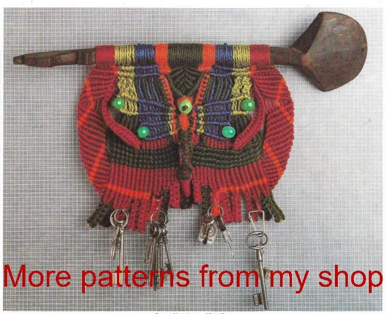 K&ouml;nnte beinhalten: Ein handgefertigter Makramee-Schl&uuml;sselhalter in Rot, Gr&uuml;n und Blau mit einem holzf&ouml;rmigen L&ouml;ffel oben. Der Schl&uuml;sselhalter hat ein Karomuster und gr&uuml;ne Perlenakzente, mit mehreren Schl&uuml;sseln, die unten h&auml;ngen. Der Text unten lautet "More patterns from my shop."