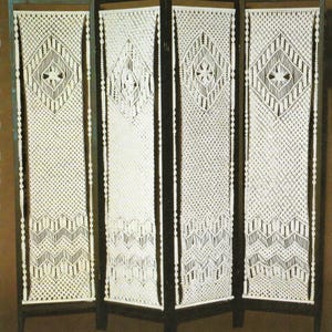 May include: A four-panel room divider made of macrame with a white cord and a dark wood frame.