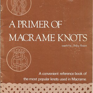 K&ouml;nnte beinhalten: Ein braunes Buch mit dem Titel "A Primer of Macrame Knots" von Mickey Baskett. Das Cover zeigt wei&szlig;e Illustrationen von Knoten und den Text "A convenient reference book of the most popular knots used in Macrame."