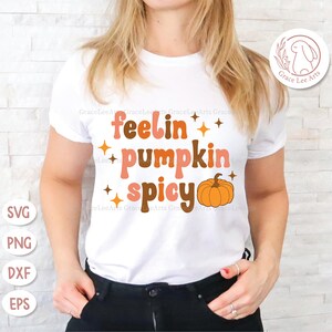 May include: White t-shirt with the text "feelin' pumpkin spicy" in a retro font with a small orange pumpkin graphic.