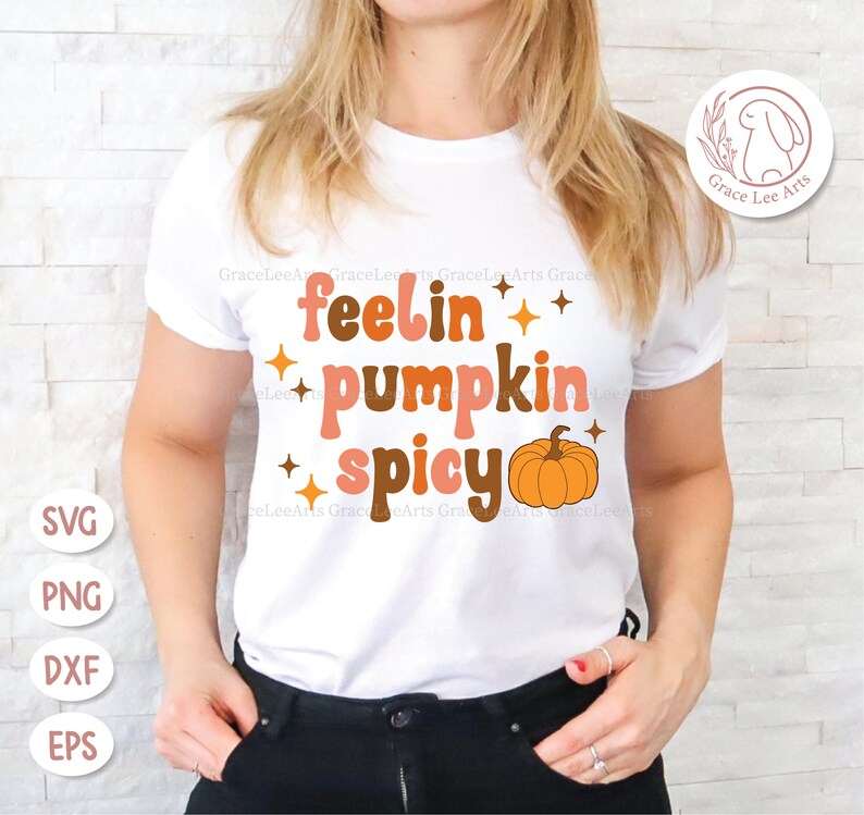 May include: White t-shirt with the text "feelin' pumpkin spicy" in a retro font with a small orange pumpkin graphic.