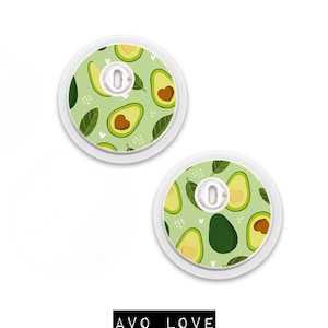 May include: Two round, white medical device covers with an avocado pattern on a light green background. The design includes avocado halves, leaves, and small white hearts. The text "AVO LOVE" is displayed in black.