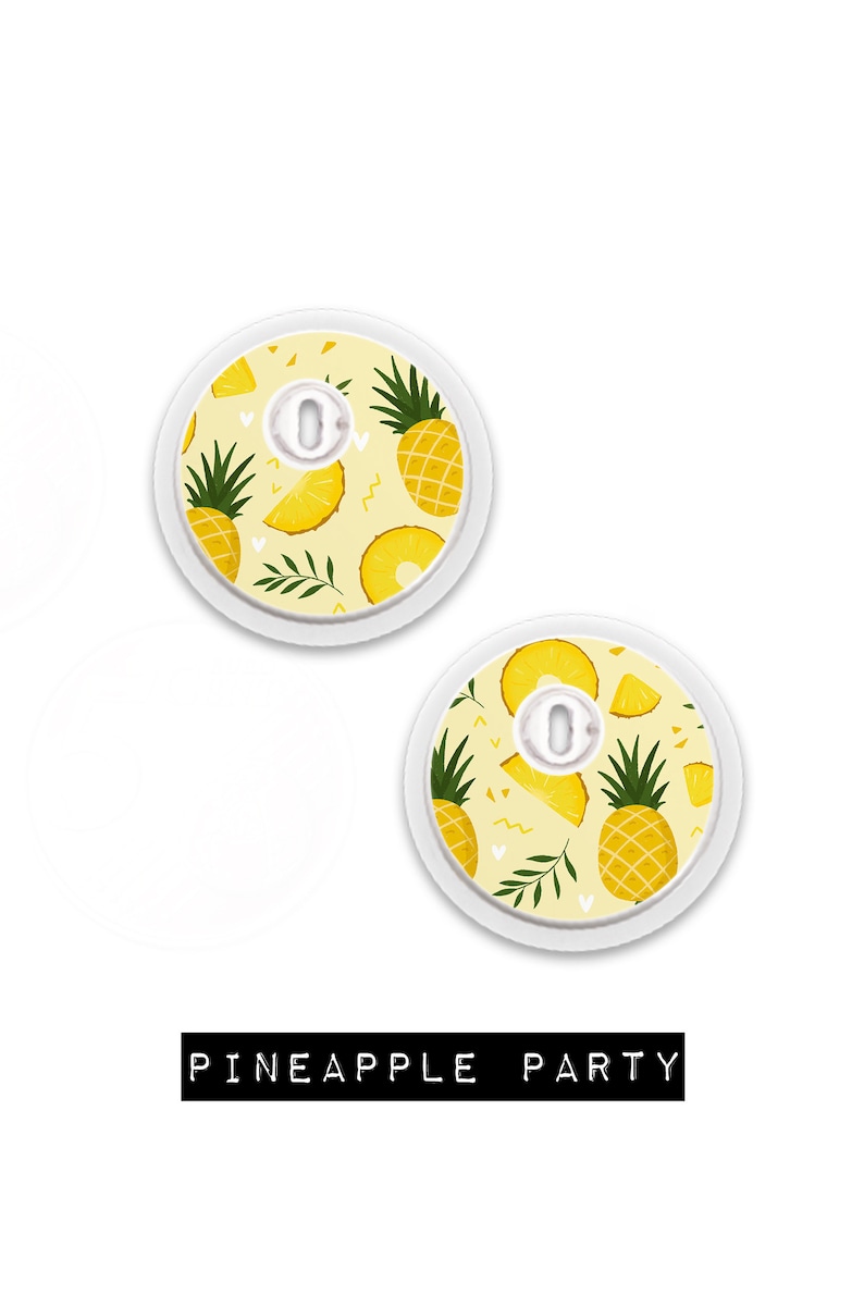May include: Two round, white medical device covers with a yellow pineapple pattern. The design includes whole pineapples, slices, and leaves on a light yellow background. The text "PINEAPPLE PARTY" is displayed in a black rectangle.