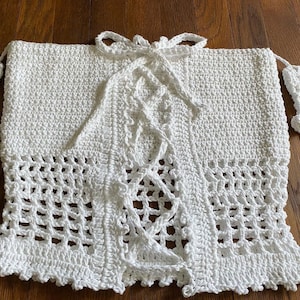 May include: White crochet top with a lace-up front and a scalloped hem.