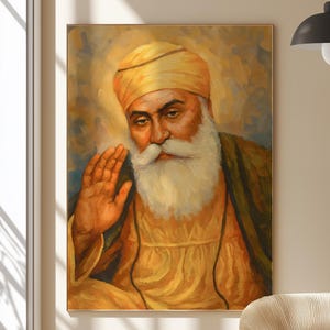 Könnte beinhalten: Ein Gemälde eines Sikh-Mannes mit weißem Bart und Turban. Er trägt eine gelbe Robe und hat einen Heiligenschein um den Kopf. Er hält seine Hand in einer segnenden Geste hoch.