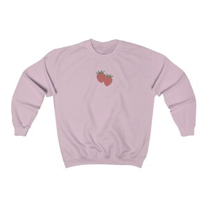 May include: A light pink sweatshirt with a simple embroidered design of two red strawberries.