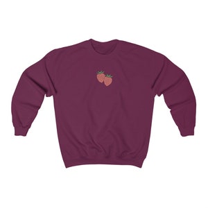 May include: A maroon sweatshirt with a small embroidered design of two red strawberries on the front.