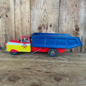 May include: A red, yellow, and blue toy dump truck with the words "Lumar Coal & Tractor" and "LM-2314" printed on the side.