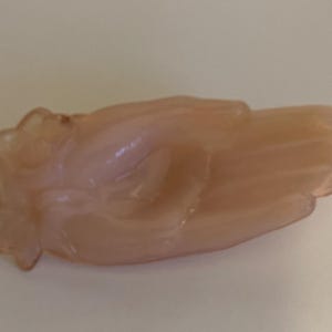 May include: A pale pink glass hand-shaped dish. The dish is shaped like a hand with the fingers curled inward.
