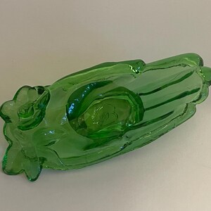 May include: A green glass hand-shaped dish with a raised design. The dish is perfect for holding small items like jewelry or trinkets.
