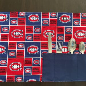 May include: A blue and red fabric cutlery roll with the Montreal Canadiens logo. The roll has a pocket for silverware and a matching tie closure. Includes a knife, fork, and two spoons.
