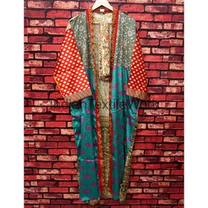 May include: A long, open-front kimono robe featuring a patchwork design with various patterns and colors. The sleeves are red with white polka dots, while the body displays teal, green, and floral prints with a central vertical patterned trim.