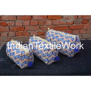 May include: Three zippered pouches with a blue and white geometric pattern. The pouches are made of fabric and have a tassel on each end.