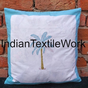 Puede incluir: Funda de cojín de algodón blanco con borde azul y diseño de palmera bordada. La funda de cojín tiene el texto "Indian Textile Work" impreso.