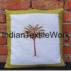 Puede incluir: Una almohada de algodón blanco con un borde verde y un diseño de palmera marrón. La almohada tiene el texto "Indian Textile Work" impreso en ella.