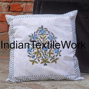 Puede incluir: Funda de almohada de algodón blanco con estampado floral azul y verde. La funda de almohada tiene un borde negro cosido.