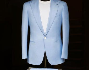 May include: A light blue suit displayed on a mannequin. The suit includes a single-breasted blazer with a white t-shirt underneath and matching trousers. The suit is tailored and has a classic design, suitable for formal occasions.