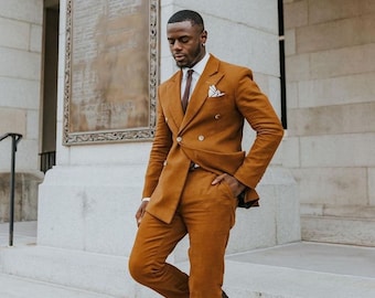 May include: A man wearing a brown double-breasted suit with a white shirt and a burgundy tie. He is standing on a set of stairs in front of a building.