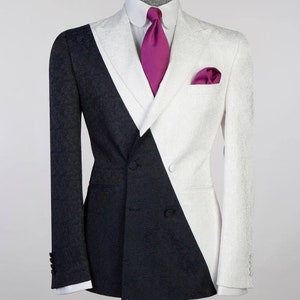 May include: A double-breasted suit jacket with a black and white design. The jacket has a pink tie and a pink pocket square.