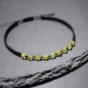 Può includere: Una collana con cordoncino nero con una fila di perline di pietre preziose verde chiaro.