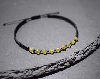 Puede incluir: Un collar de cordón negro con una fila de cuentas de piedras preciosas verde claro.