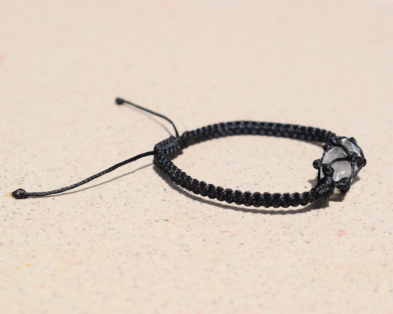 May include: A black braided bracelet with a clear crystal charm.