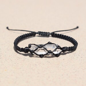 May include: A black cord bracelet with a clear quartz crystal wrapped in the cord.