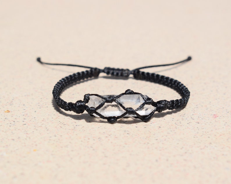 May include: A black cord bracelet with a clear quartz crystal wrapped in the cord.