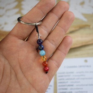 May include: A keychain with seven chakra beads in the colors of the rainbow, attached to a silver ring and black string.