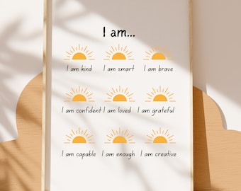 May include: A framed print with the words "I am..." at the top. Below are the phrases "I am kind, I am smart, I am brave, I am confident, I am loved, I am grateful, I am capable, I am enough, I am creative" with a yellow sun graphic.