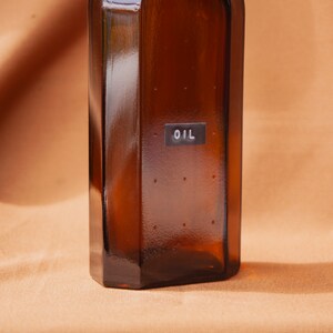 May include: A brown glass bottle with a label that says "OIL" on it.