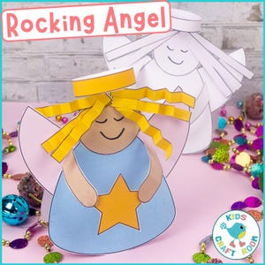 May include: A handmade paper angel craft with the text "Rocking Angel". The angel has a blue dress, yellow hair, and a gold star. A second, uncolored angel is in the background. The image is on a pink surface with decorative beads.
